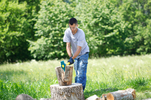 Les Mains Dans Des Gants De Protection Tiennent La Hache Pour Casser Le Bois  De Chauffage Pour Le Fendre En Morceaux